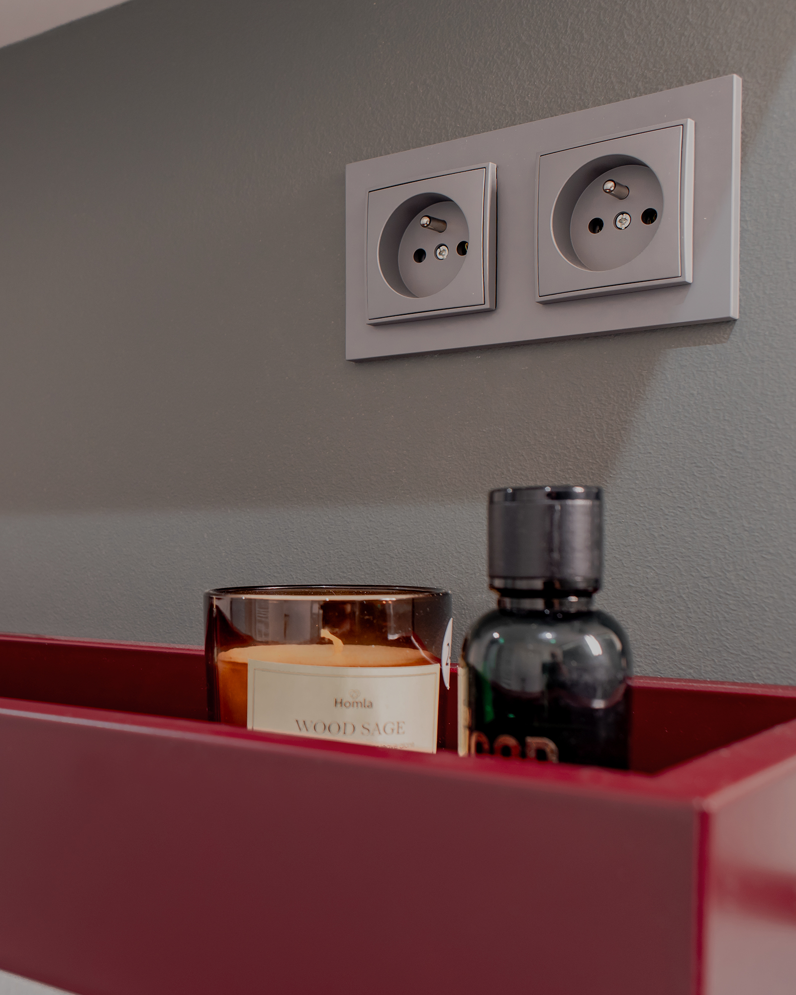 Choć króluje tu szarość i złamana biel, to pojawia się także zgaszona zieleń na ścianach, podkreślona półeczką w głębokiej czerwieni.